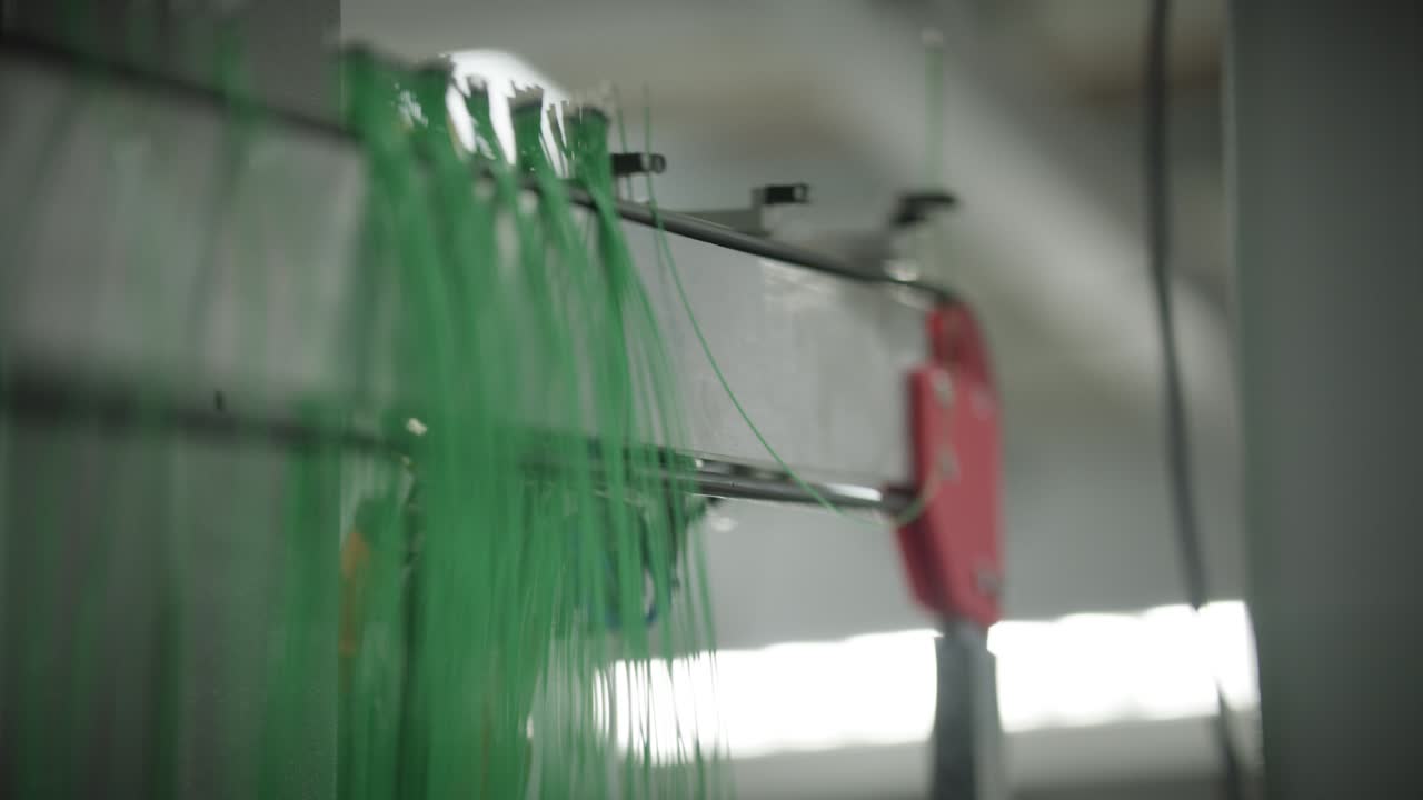 Robot automatizado cuelga cables terminados de sensores de temperatura en un estante de almacenamiento.