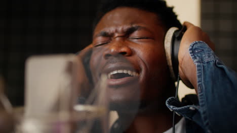 young male artist singing into a microphone in a recording studio