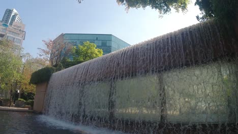 1-2 super slow panaramic view outwards of modern city building with water falls and wake pool to wash feet during hot summer days of refreshing cool off by the marble exterior stone steps