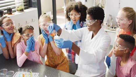 maestra diversa y escolares felices teniendo clase de ciencias en el laboratorio escolar