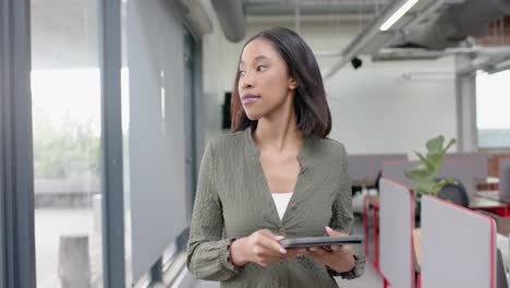 African-american-businesswoman-using-digital-tablet-while-walking-in-office