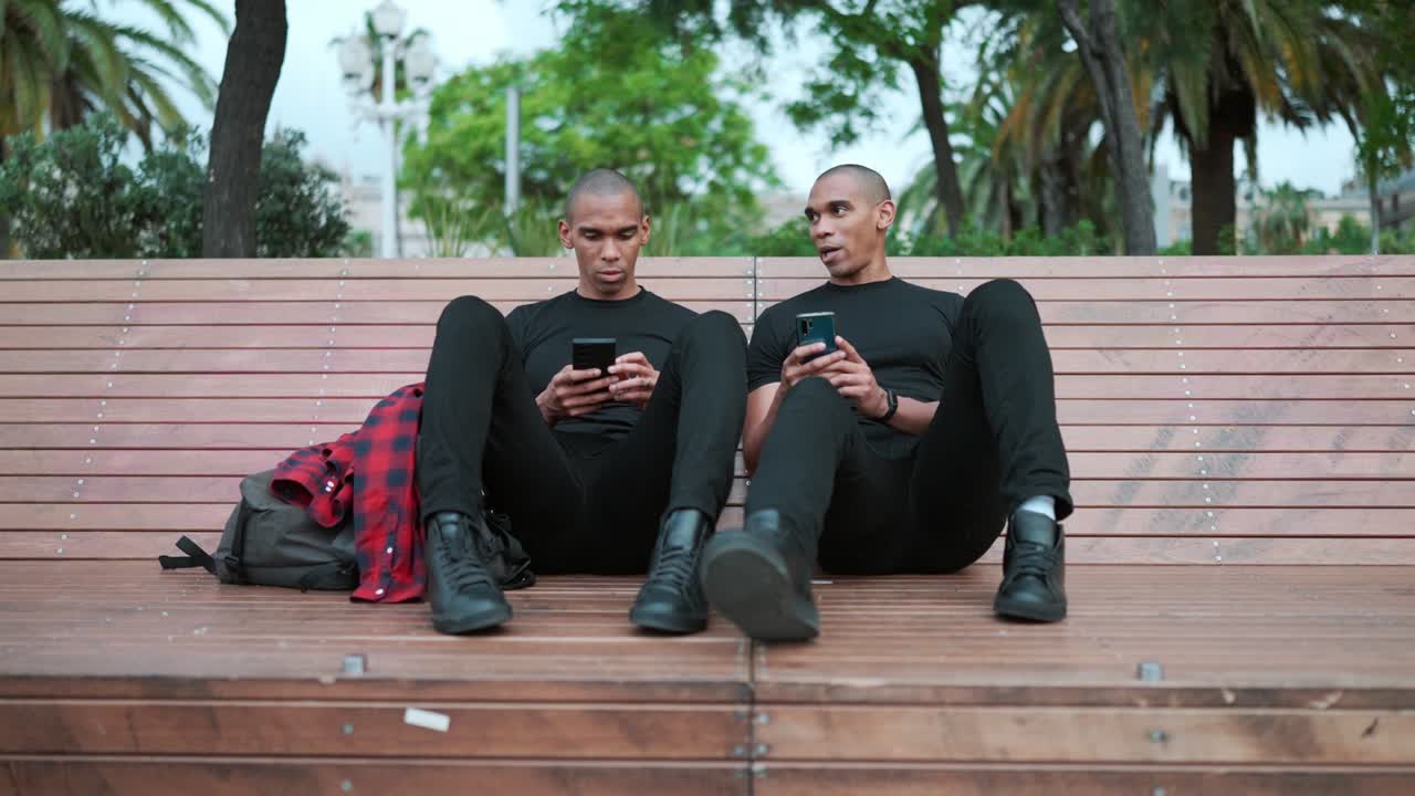Two confident bald brothers talking and typing on phone