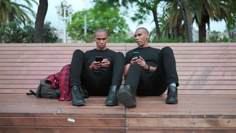 two confident bald brothers talking and typing on phone