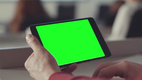 persona sosteniendo una tableta con una pantalla verde en un entorno de oficina