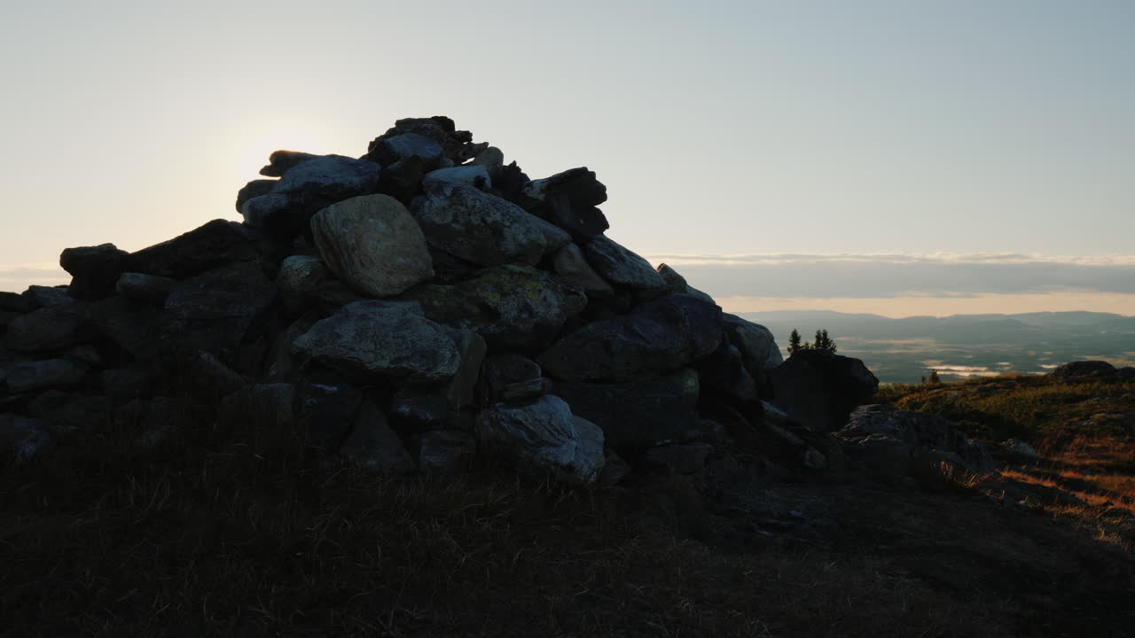 un pequeño montículo de piedras se encuentra en la cima de la montaña los rayos del sol naciente brillan debido a