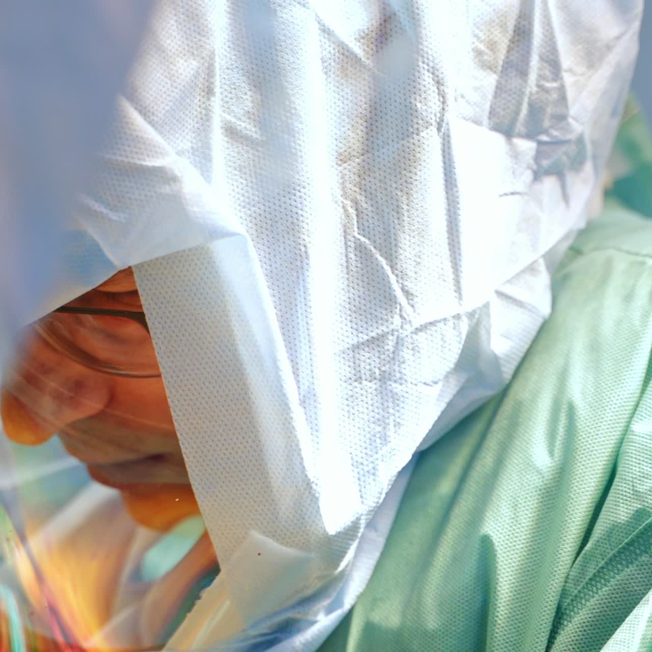 Mid aged male surgeon in glasses and protective suit speaks to his colleagues collaborating at surgery. Close up portrait of a medic at work