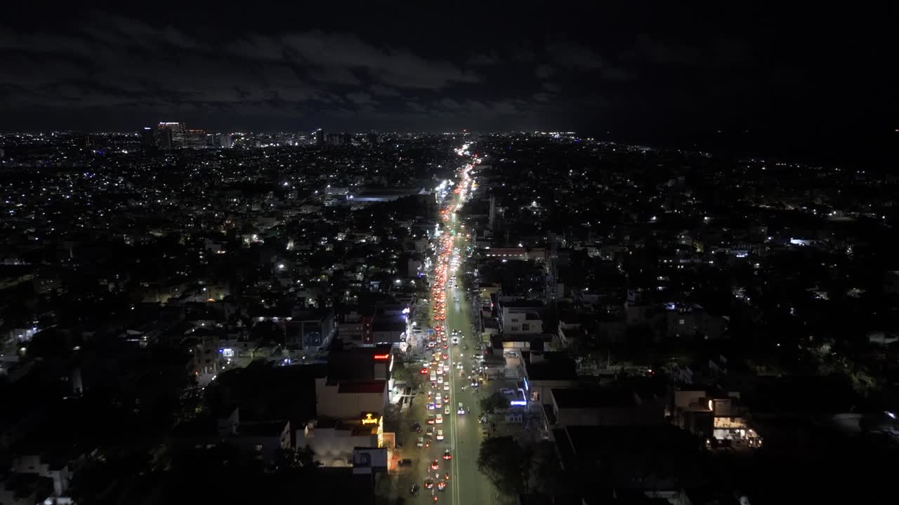 Lit up streets of city with traffic jam during night. Aerial view.