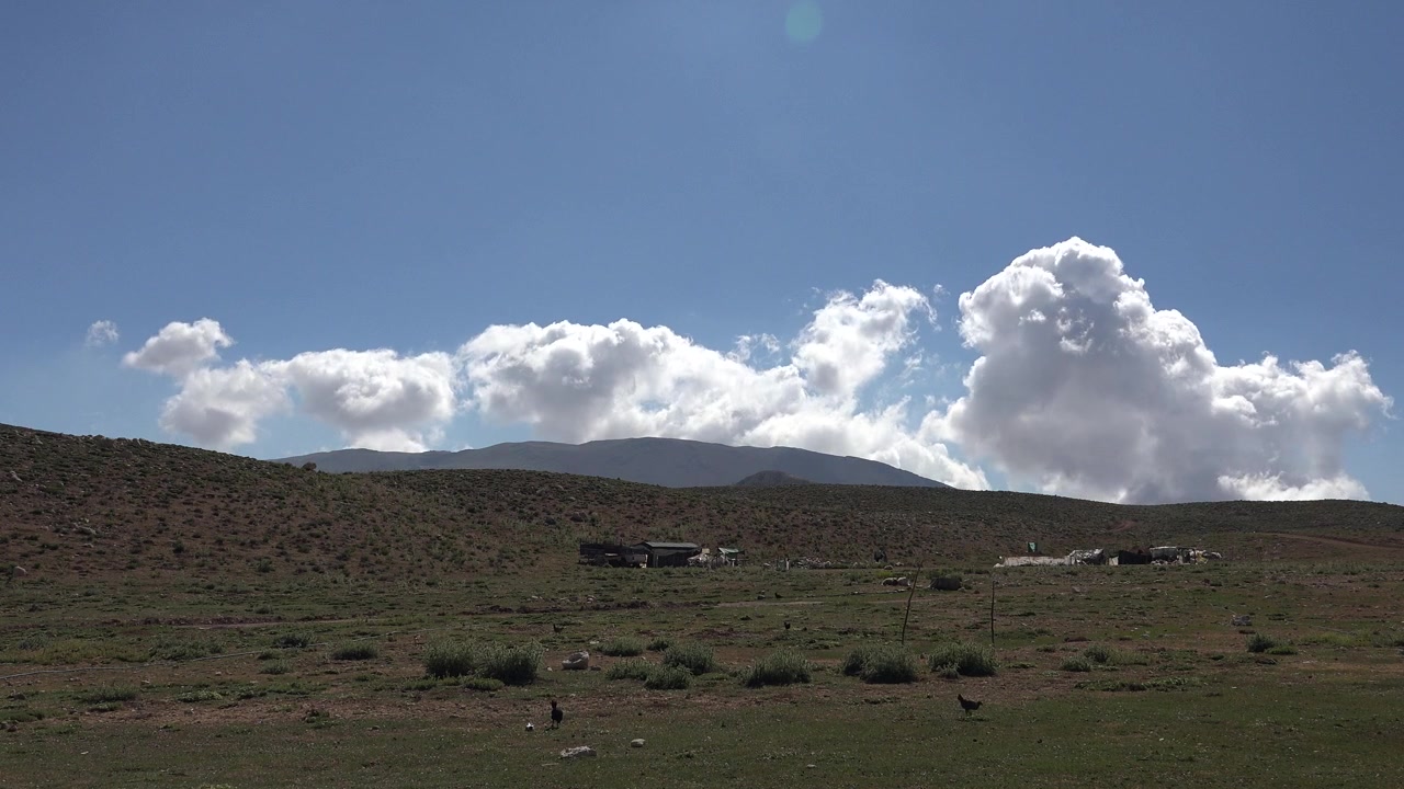 Paesaggio suggestivo con dolci colline e montagne distanti sotto un cielo azzurro nuvoloso