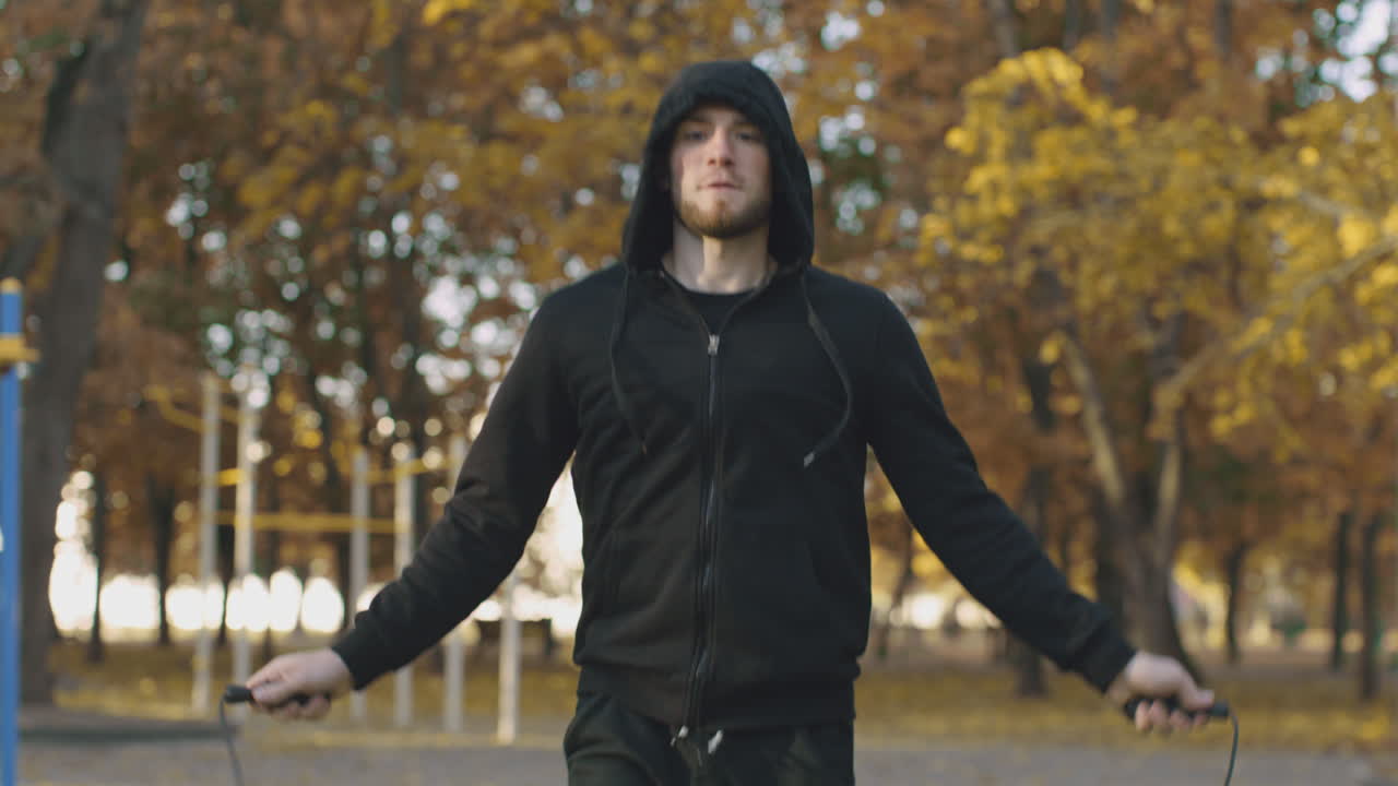 Uomo che salta la corda in un parco autunnale