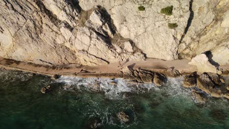 aerial reverse shot panning up with drone on the coast of beska in croatia with a woman walking next to mountain and the adriatic sea