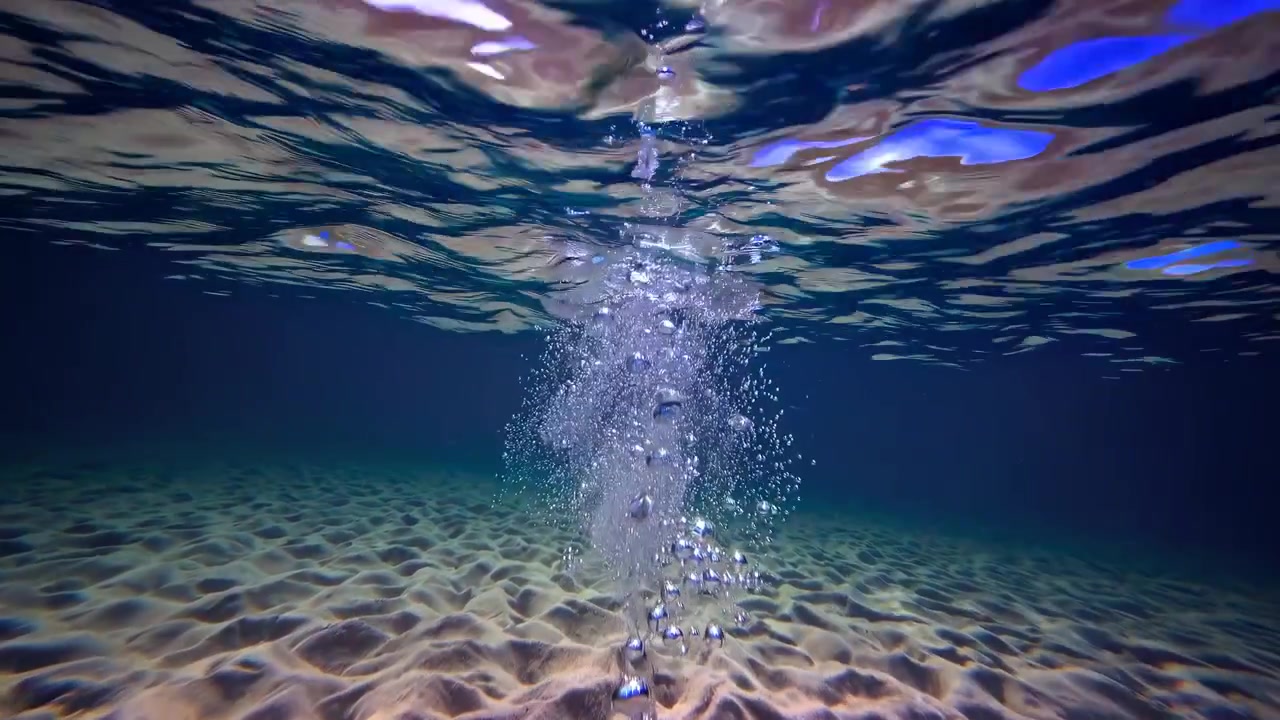Vista subacquea di bolle che salgono dal fondale oceanico sabbioso