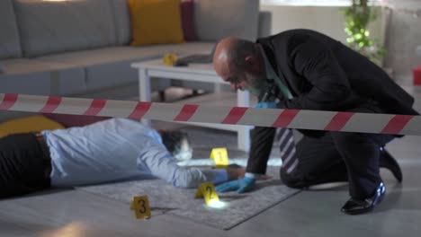 Prosecutor-man-examining-body-at-crime-scene-surrounded-by-barricade-tape.