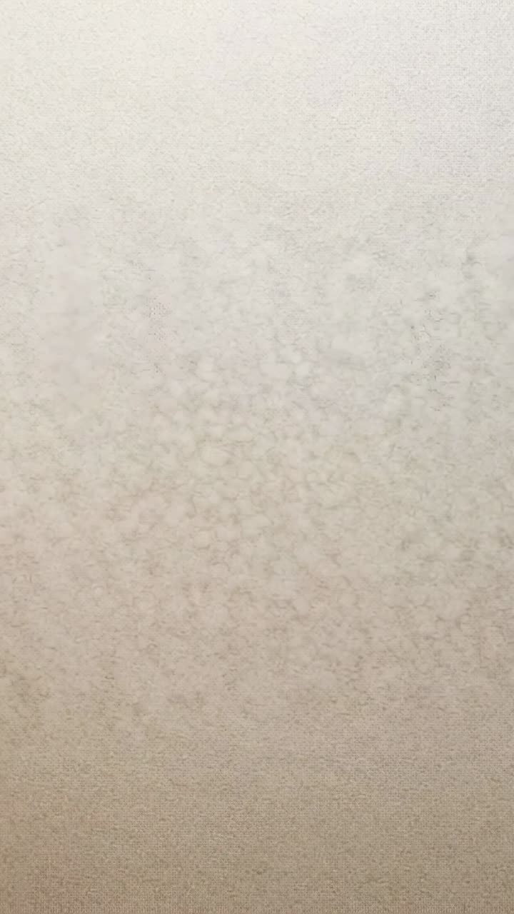 Vertical video: Starting camera holding fixed on light beige interior wall, showing uniform finish