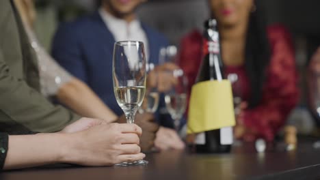 Close-Up-Shot-of-Glass-of-Champagne-On-Table-as-Friends-In-Background-Celebrate-New-Years