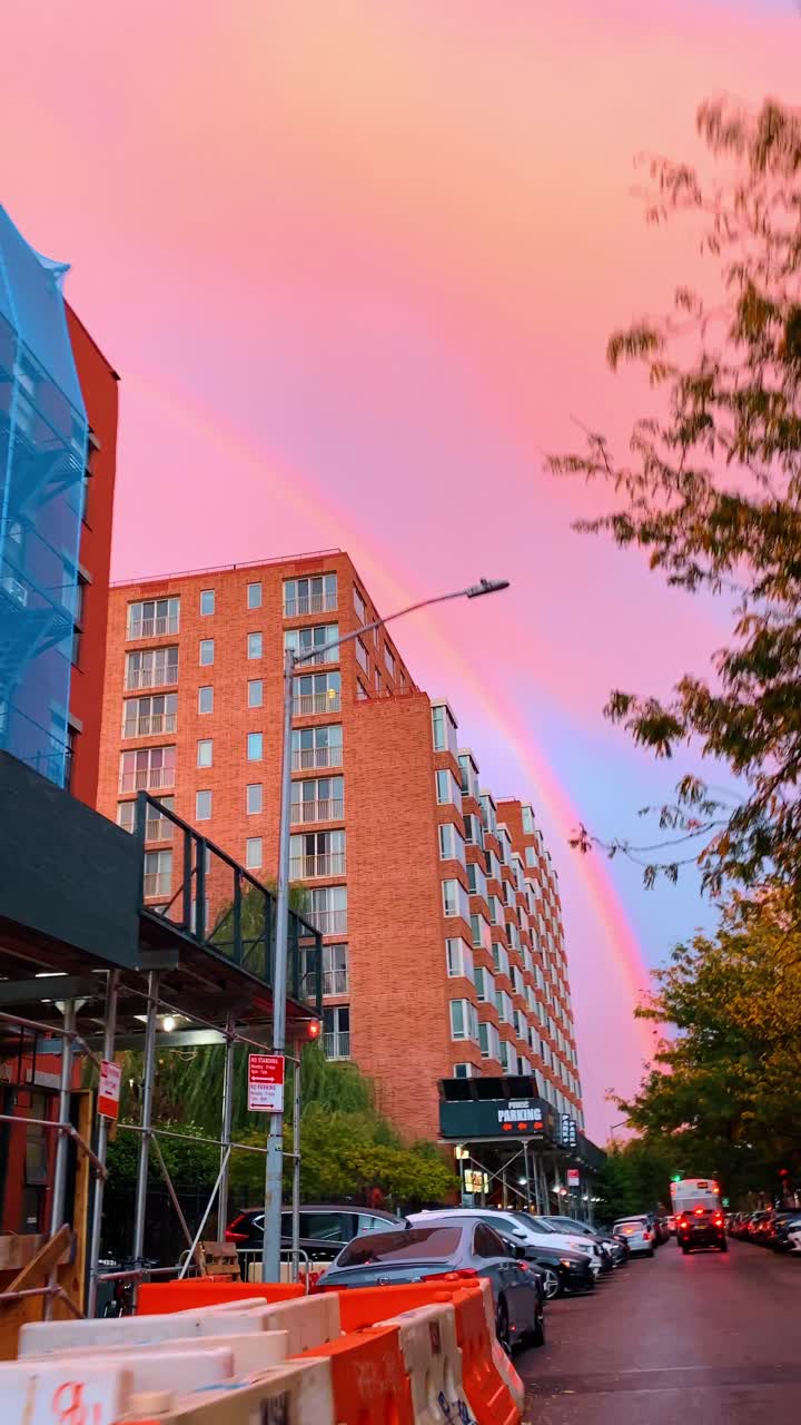 Nueva York, EE. UU., 25 de septiembre de 2025: Doble arcoíris sobre una calle urbana con barreras de construcción. Doble arcoíris en un cielo rosado sobre edificios de la ciudad y barreras de construcción naranjas al anochecer