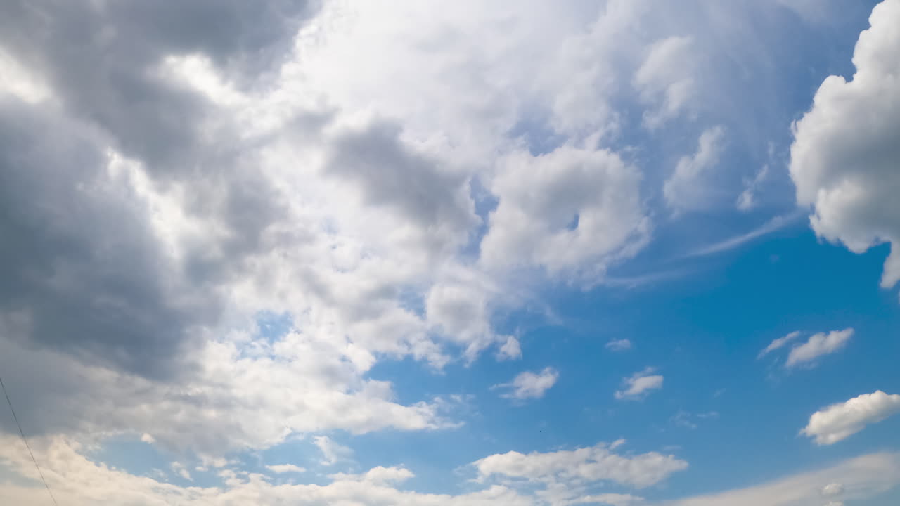 Blue summer sky with light soft clouds. Soft white cloudscape lit by the bright sun. Timelapse.
