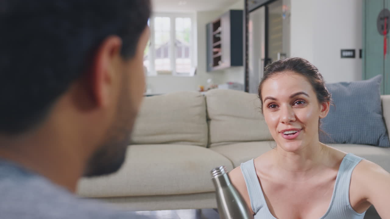 Couple at home chatting after exercising at home together - shot in slow motion