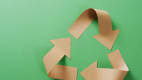 primer plano del símbolo de reciclaje de flechas de papel sobre fondo verde, con espacio para copiar