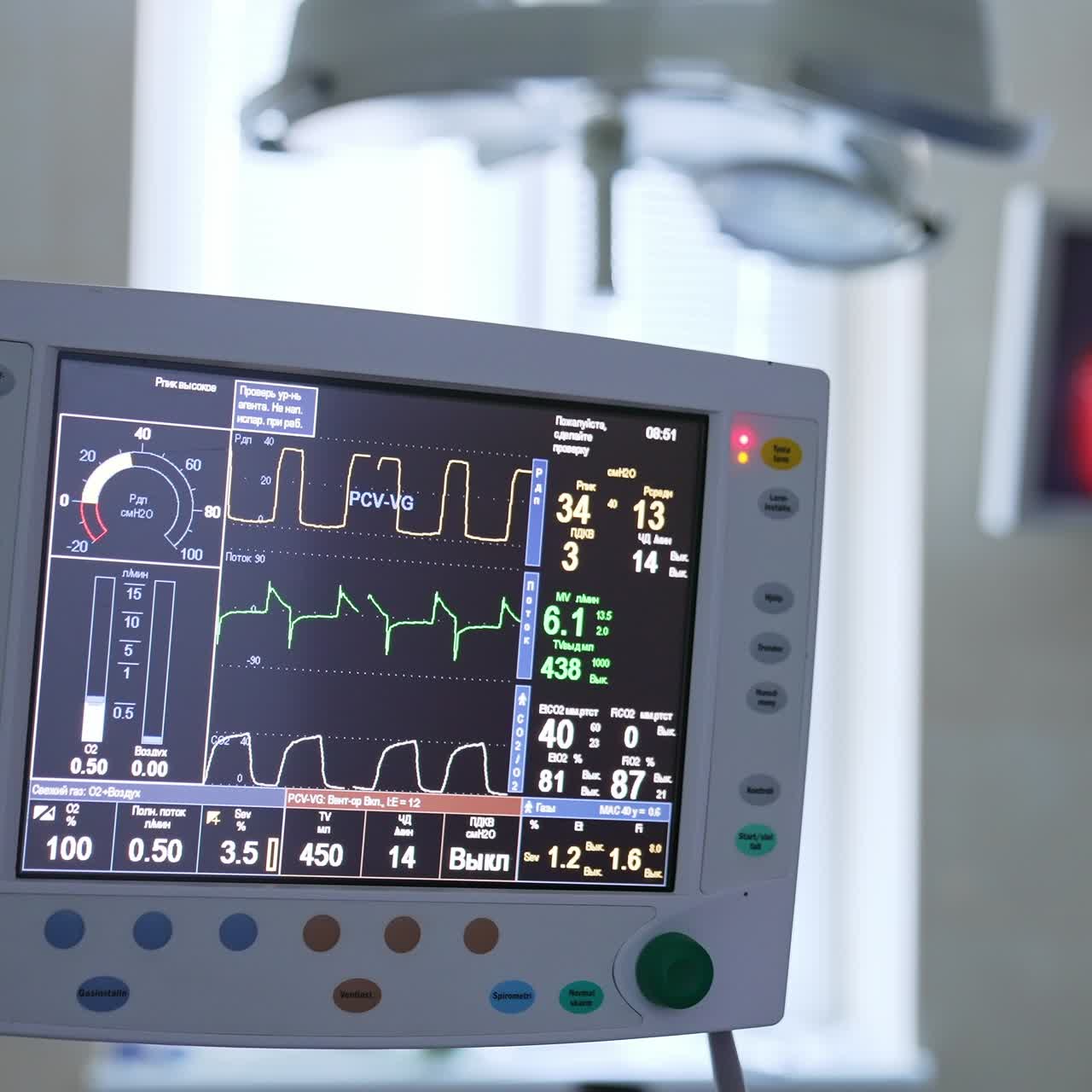 Working equipment in operational theatre during operation. Screen with vital parameters at foreground. Monitor with surgery process at the backdrop in blur