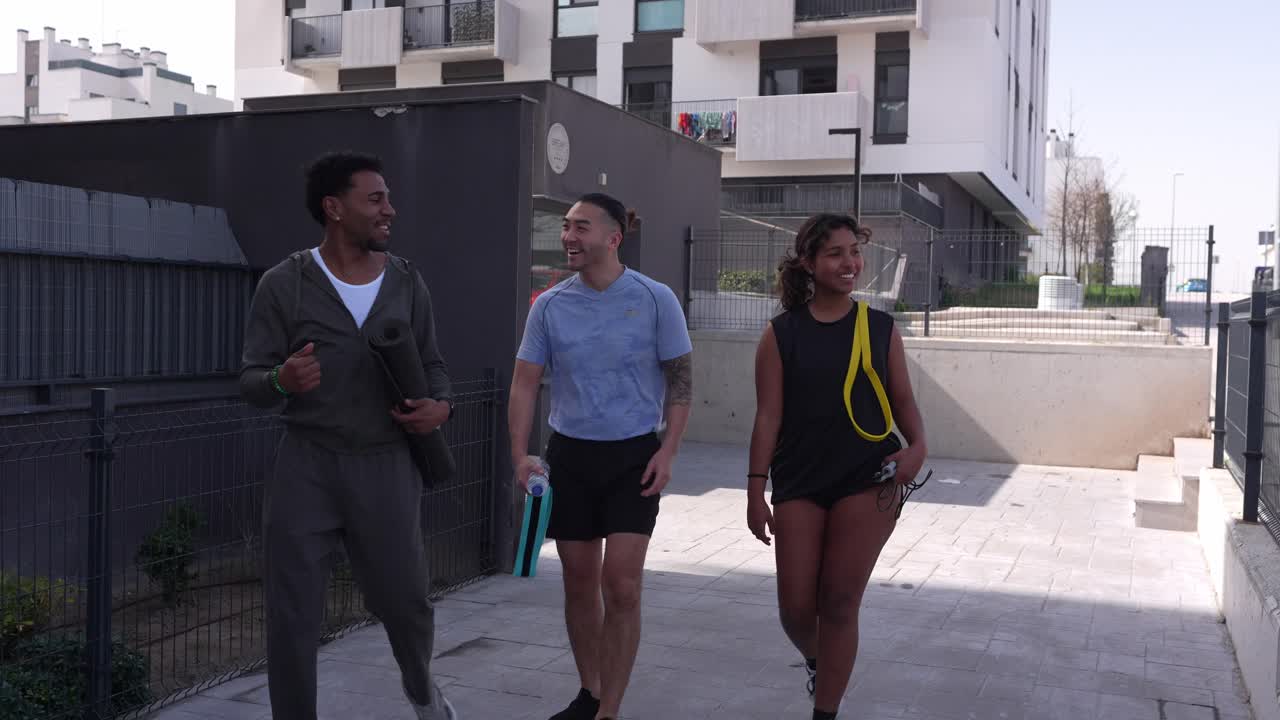 Three Happy Friends Walking and Talking in Urban Area with Exercise Gear