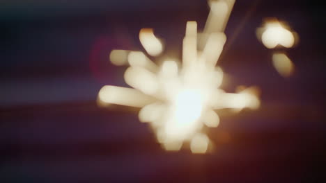 close-up-sparkler-firework-burning-bright-on-beach-background-at-night-new-years-even-celebration-concept