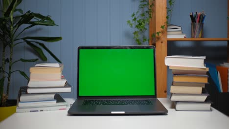 green screen laptop computer on a homework desk with books