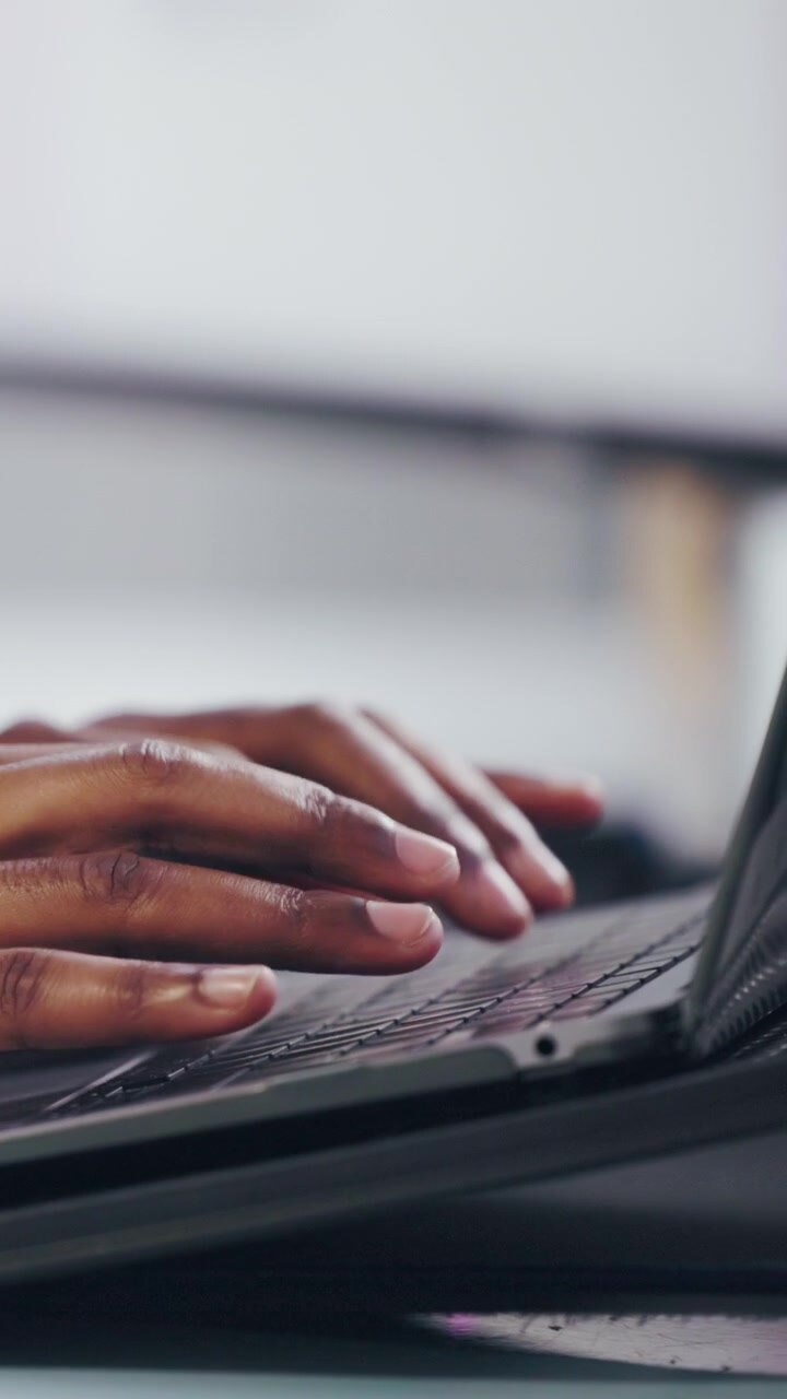 Primo piano di una persona che digita sulla tastiera del laptop in ufficio