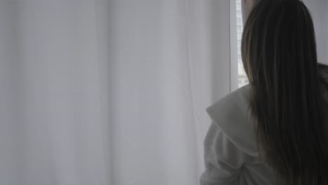 Close-up-back-view-young-woman-closing-the-curtains-in-her-apartment