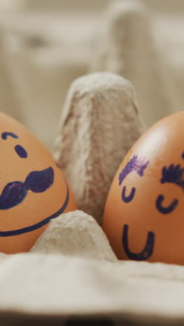 video de primer plano de dos huevos marrones con caras dibujadas en el fondo de un cartón de huevos