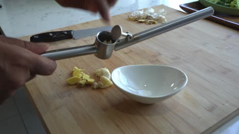 using a garlic press to mince garlic and ginger