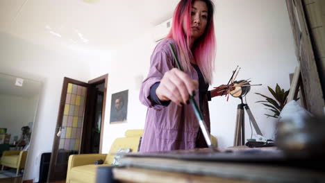 artista visual coreano de pelo rosa pintando en casa estudio