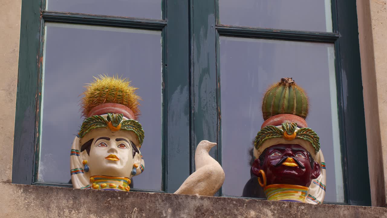 Sicilian Moorish Heads with cactus inside hanging outside a window in Taormina, Sicily, Italy (Sicilia, Italia), blending culture with nature