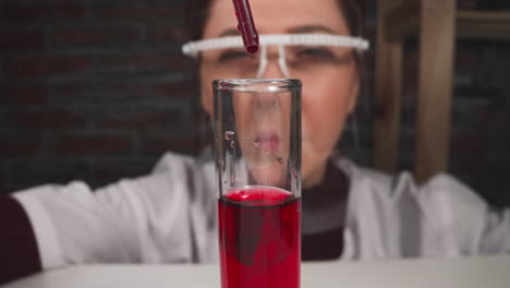 el asistente de laboratorio gotea sangre en el tubo de ensayo con reactivo