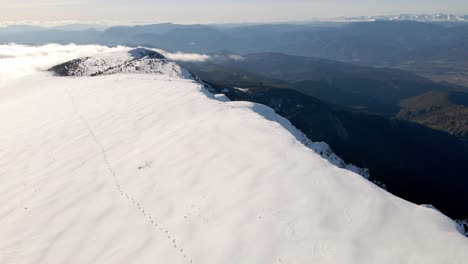 Aerial-views-of-a-mountain-range-in-the-spanish-Pyrenees-coverd-by-snow-and-with-clouds-in-the-horizon