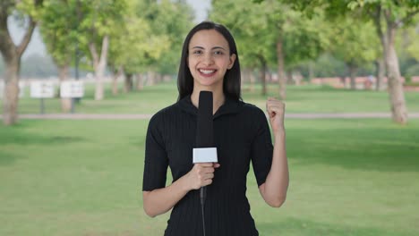 happy indian female news reporter talking to the camera