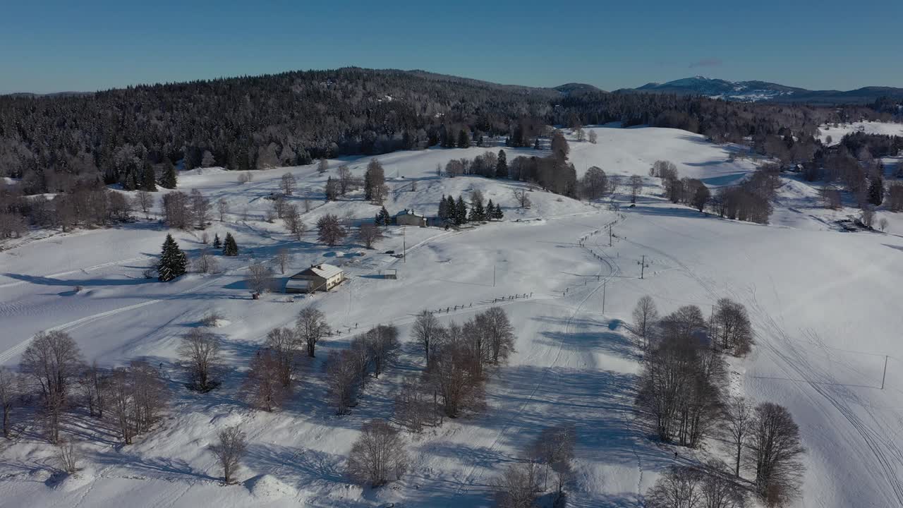 아름다운 겨울 풍경과 햇빛 아래 쥐라 산맥에서 스키를 타는 크로스컨트리 선수들의 군중을 보여주는 공중 역방향 촬영