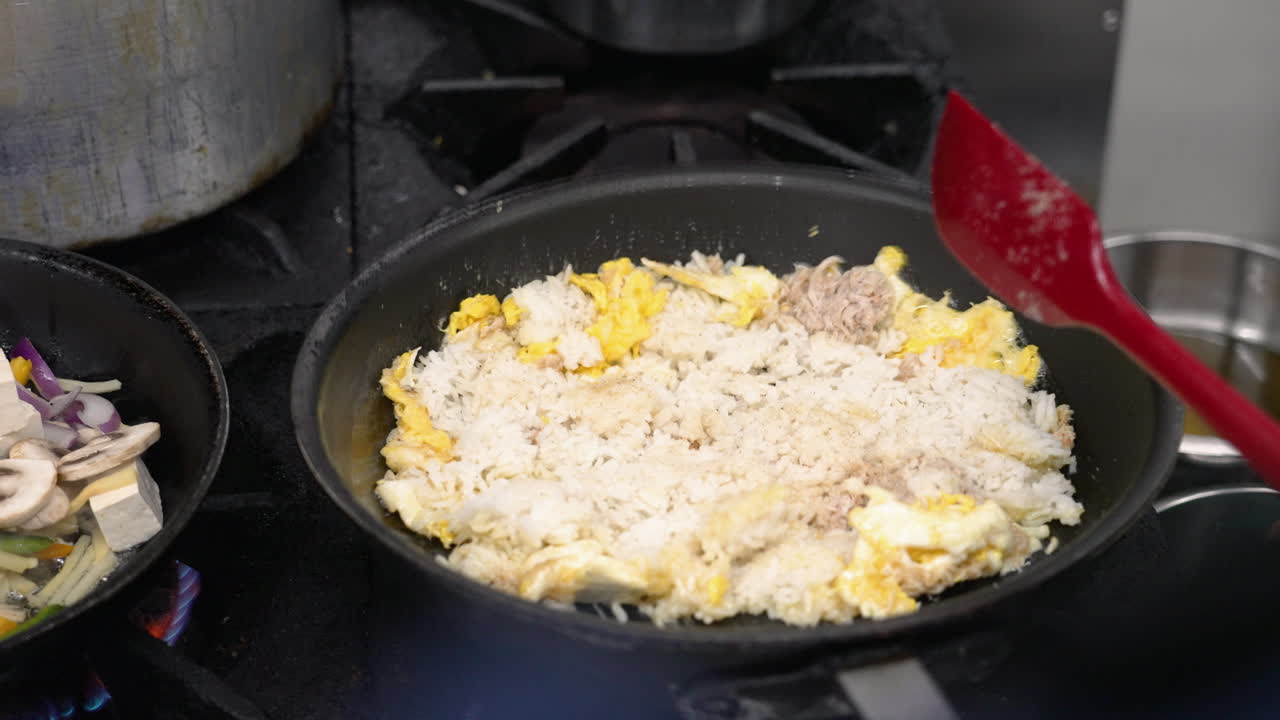 요리사는 레스토랑 부에서 상업용 스토브에서 불타는 불 위에  과 달을 뒤집습니다.