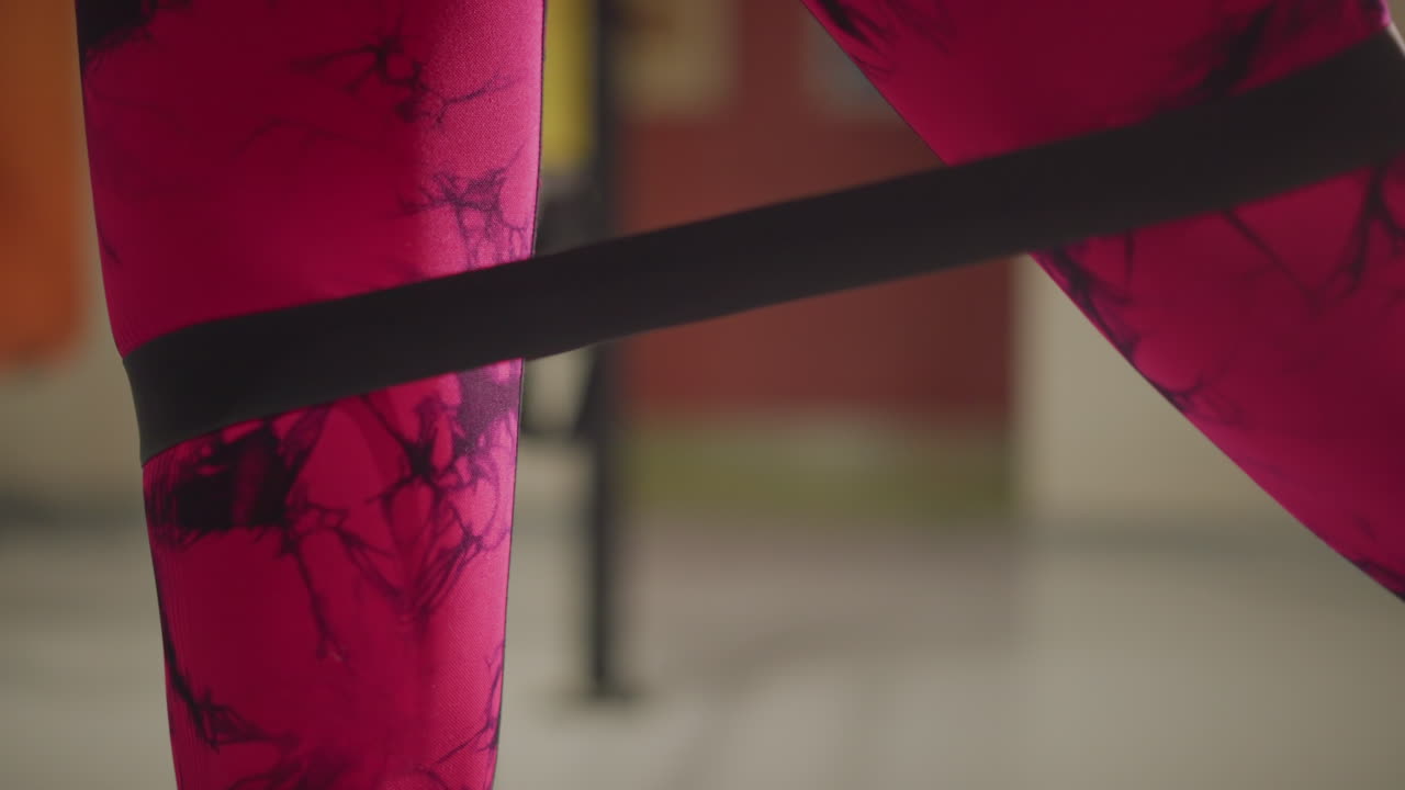 banded lateral step for glute activation closeup of knees with mini band at joint showing female athlete in patterned pink leggings controlling tempo, emphasis on knee alignment and muscle