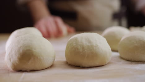 The-baker-rolls-out-the-dough-for-buns-on-the-board.-Working-in-a-bakery