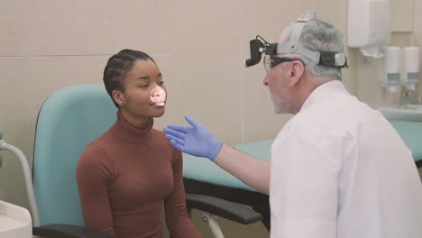 an old male doctor does a physical check and ask questions to a female young patient in his clinic