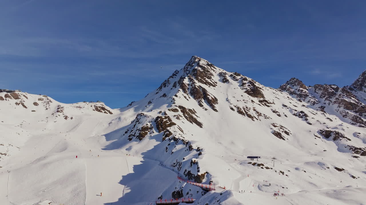 Piste da sci animate piene di sciatori e seggiovie in funzione in una luminosa giornata invernale sulle Alpi.