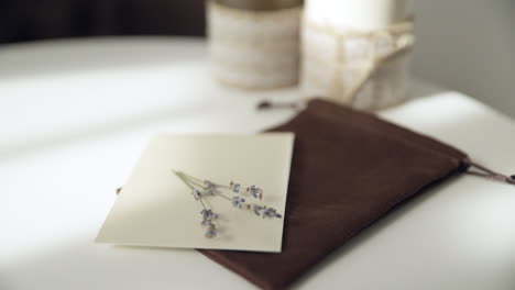 hermosa mano femenina escribiendo una invitación de boda o vacaciones en una mesa blanca brillante con velas