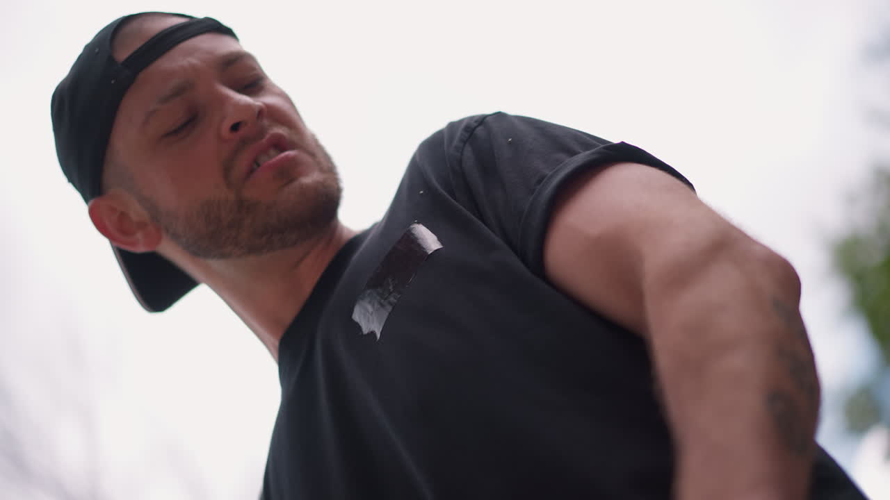 White Male Tattooed Forearm Pulling Red Resistance Band From Low Angle, Determined Athlete Showing Forearm Veins And Focused Motion, Dramatic Sky And Tree Canopy Visible, Powerful Pull And Firm Grip