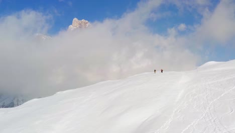 isolated group of hikers on top of snow-capped dolomites mountain