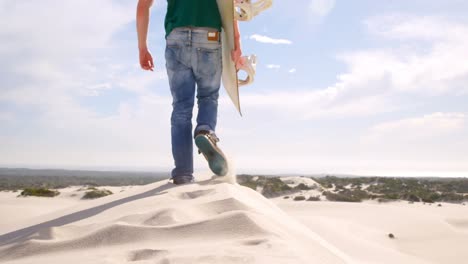 hombre caminando con tabla de arena en el desierto 4k