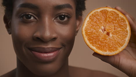 mujer sosteniendo una rebanada de naranja