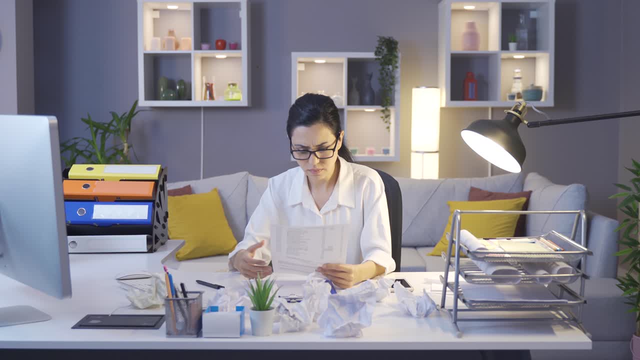 una mujer de negocios frustrada arrugando papeles.