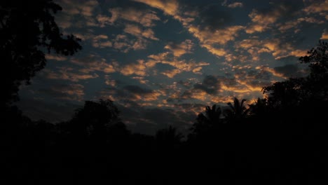 nubes naranjas oscuras moviéndose a través del cielo nocturno, siluetas oscuras