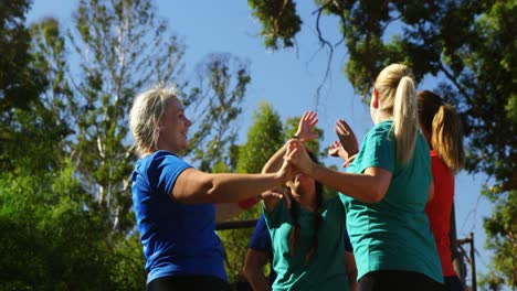 Grupo-De-Mujeres-En-Forma-Chocando-Los-Cinco-Entre-Sí-Durante-La-Carrera-De-Obstáculos