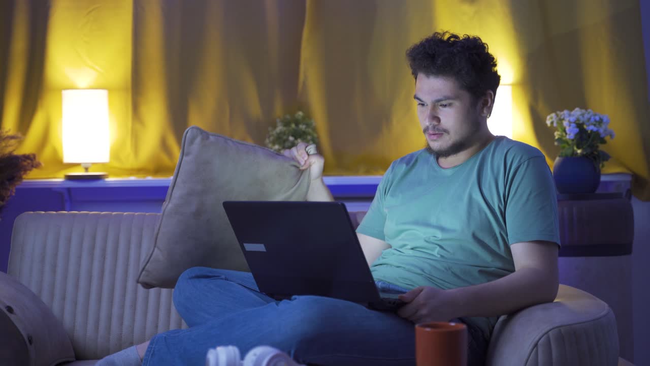 hombre viendo una película de terror en el portátil por la noche. el hombre está asustado y tenso.